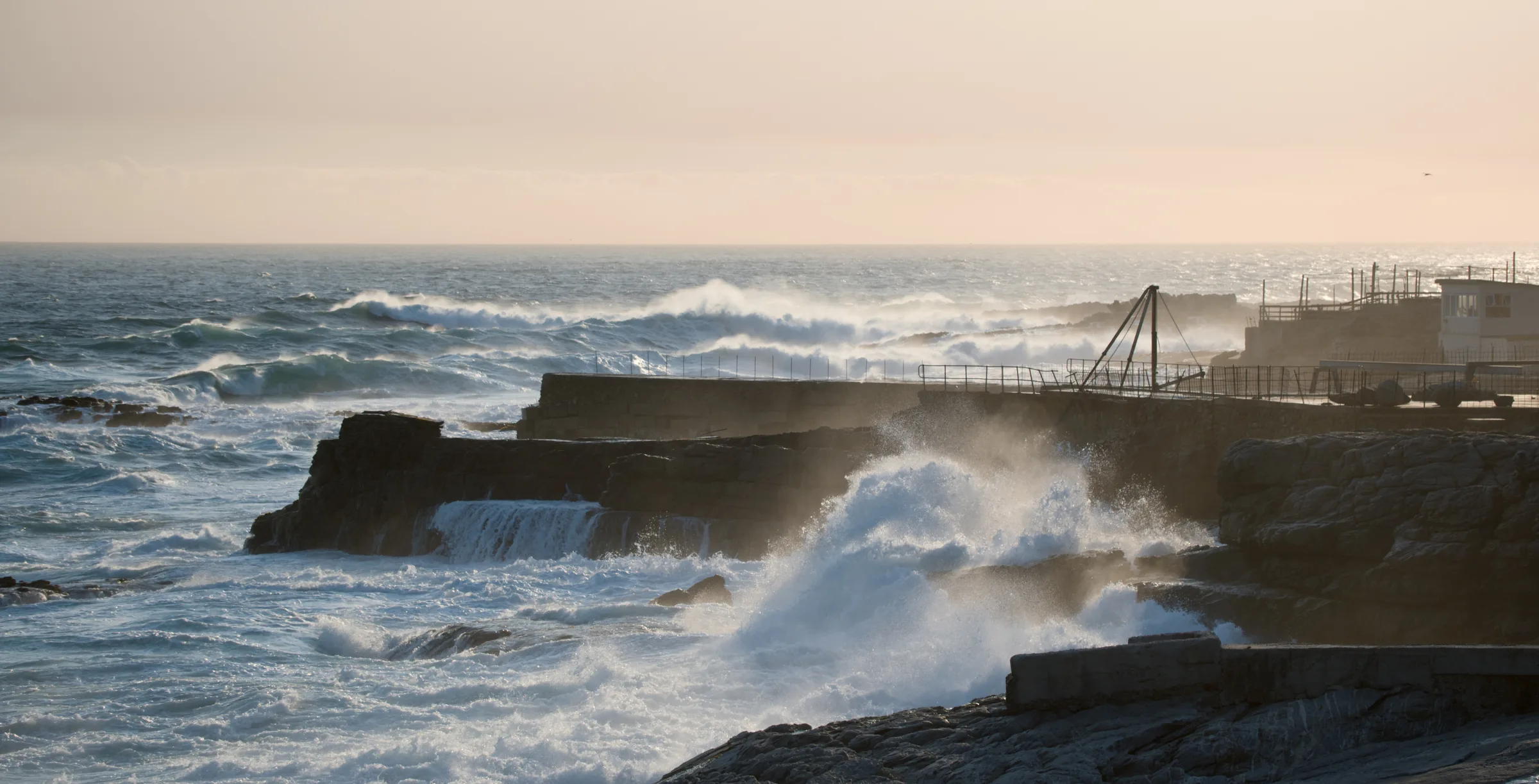 Heavy surf breaking against the rocks at a tidal pool, spray catching the light